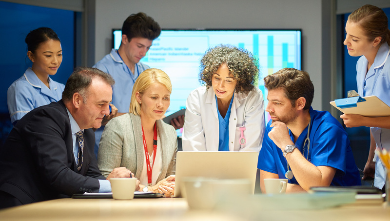 A multidisciplinary ground of health professionals looking at a computer